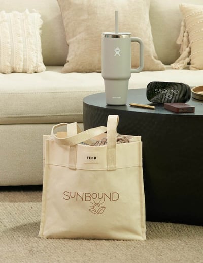 a canvas bag sitting next to an end table with a cup