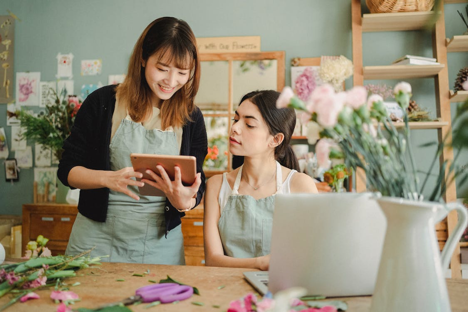 Create a Custom Company Store blog cover image - woman in flower shop showing a tablet