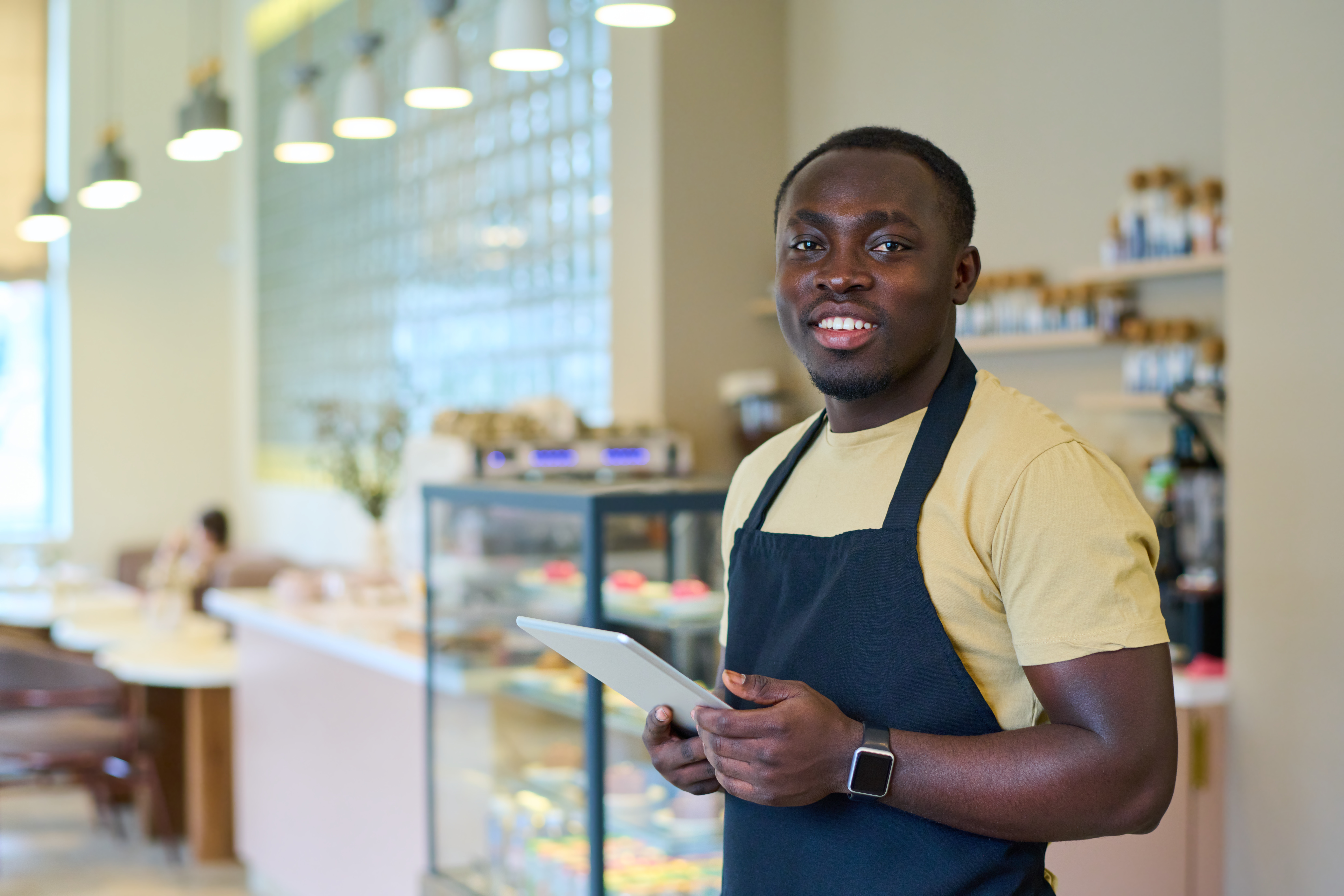 uniformed waiter taking an order on a tablet at a bakery