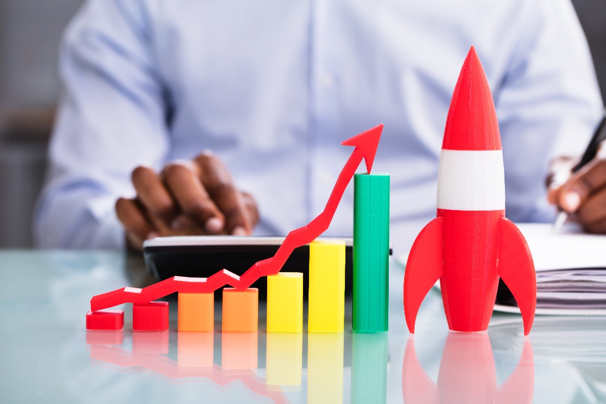 man working in a background with a rocket ship and upward chart in the foreground