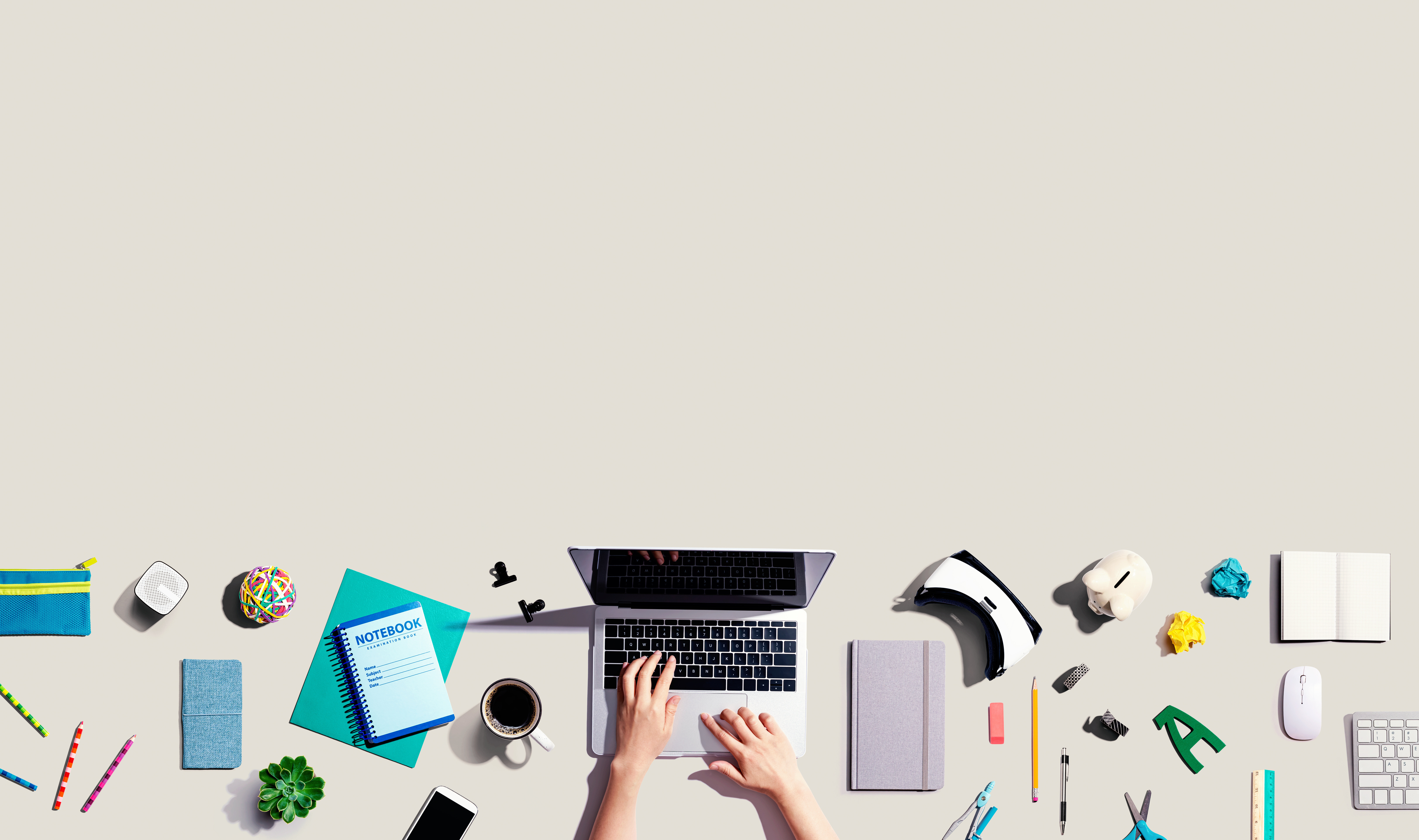 a beige background with the bottom of the image showing someone's hands working on a Macbook next to a variety of promo products including a coffee mug, pens, binder, speaker, notebook, and other material - Plan Your 2025 Marketing Mix blog cover image