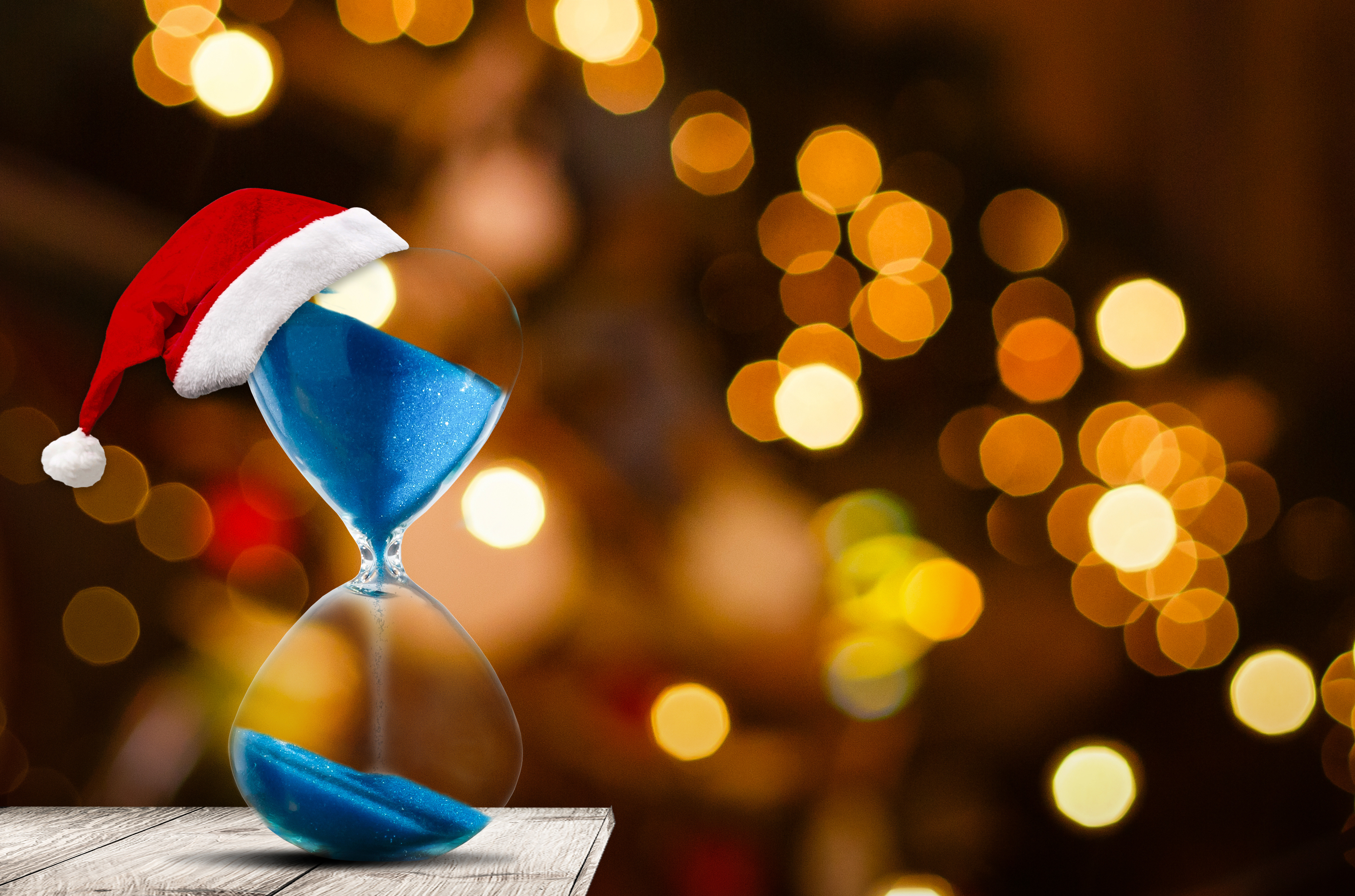 hour glass with a Santa hat on the top, pouring blue substance, in front of holiday lights - Rush Order Gift Ideas Buying Guide blog cover image