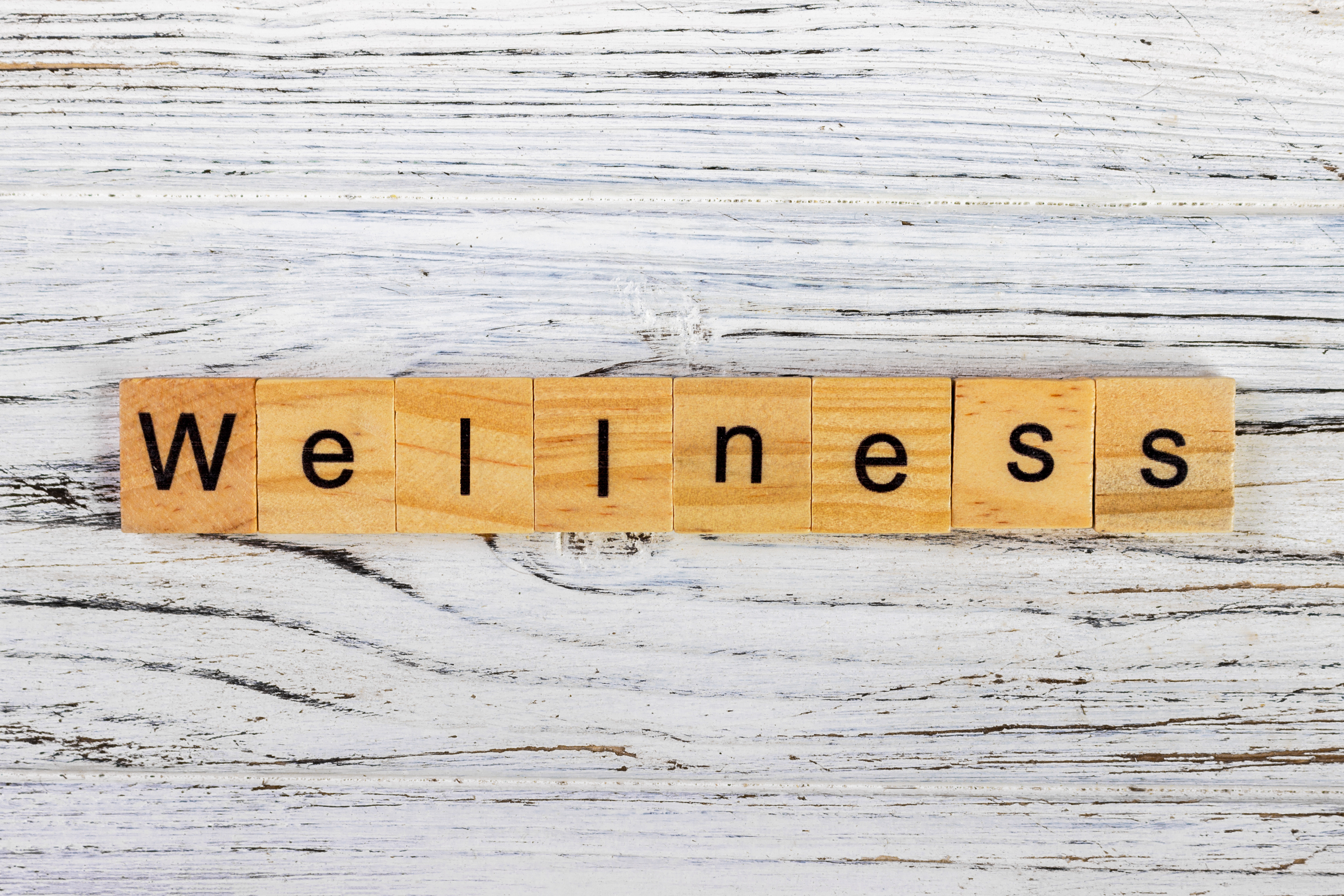 'Wellness' spelled out with wooden block letters on a white background